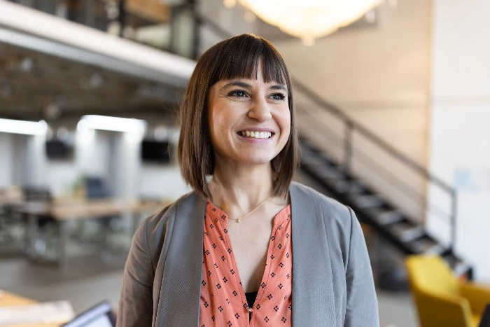 Image of a smiling businesswoman standing in office and looking away.