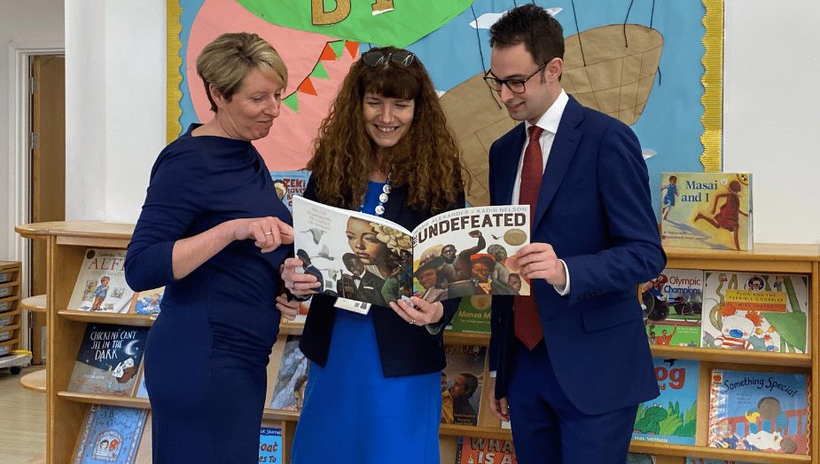 ESF Director Jo Pountney reading a book alongside Manor Fields Primary Headteacher Helen Smith and Hertford and Stortford MP Josh Dean.