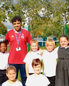 Photo of a community activator apprentice with a group of pupils in a community sports setting