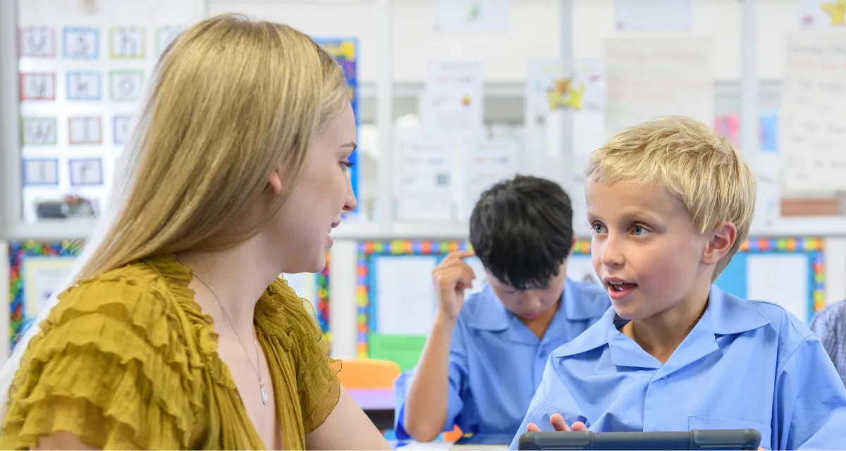 A teaching assistant helps a child with SEND use assistive technology