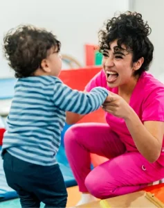 An apprentice nursery nurse helps a young boy learn to walk