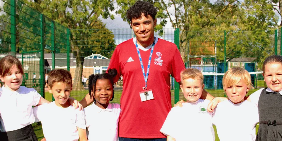 a sports apprentice stands next to a group of children