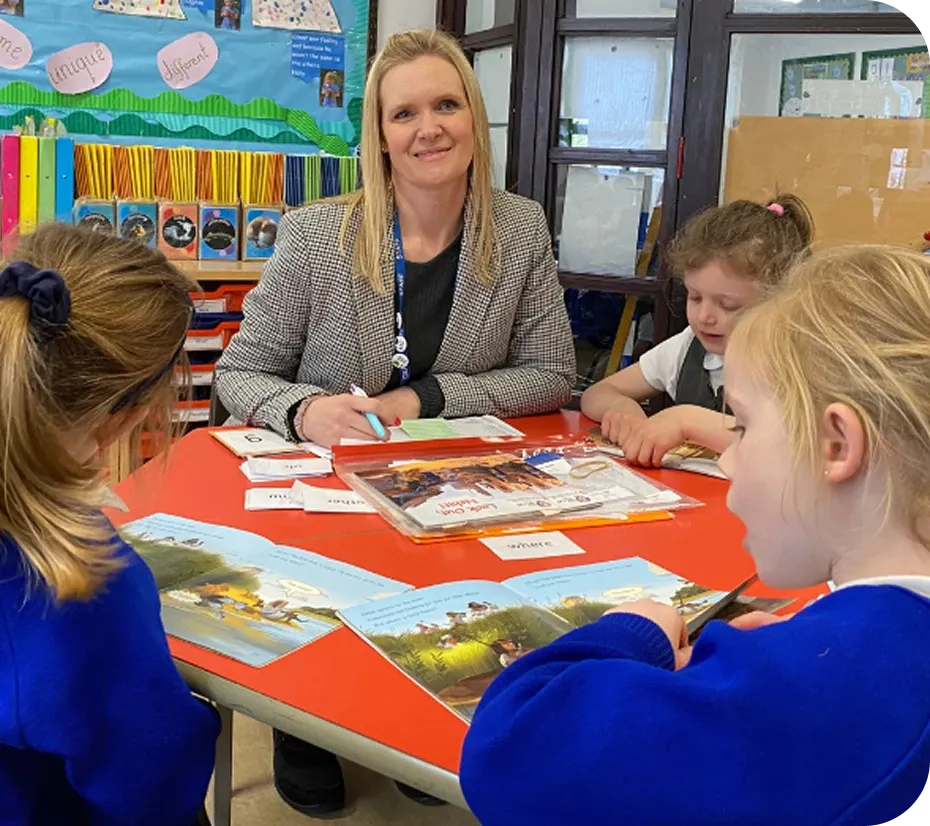 A teaching assistant conducting a literacy intervention with a small group of pupils